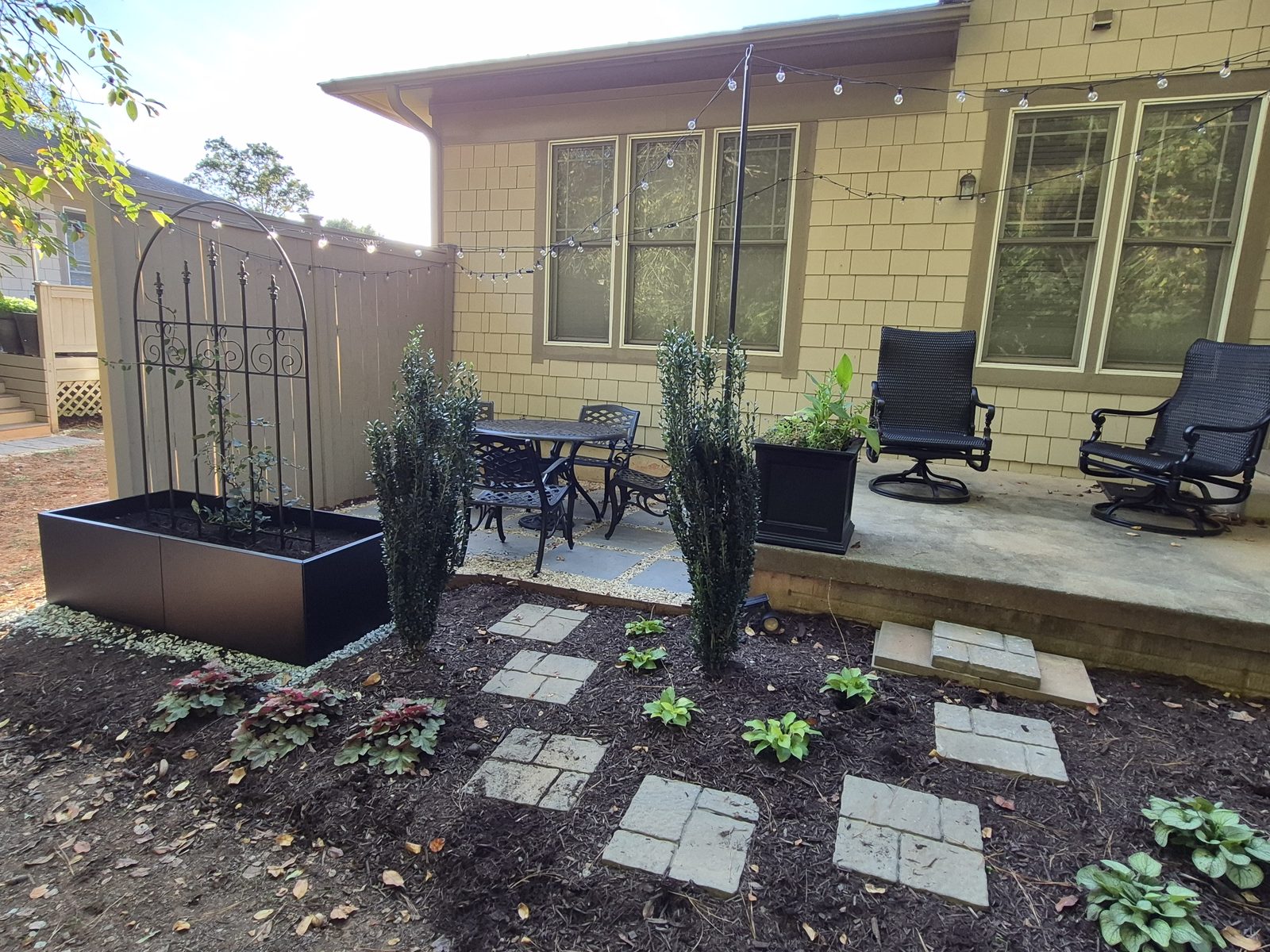 Raised steel planter, trellis, and boxwood spirals newly installed