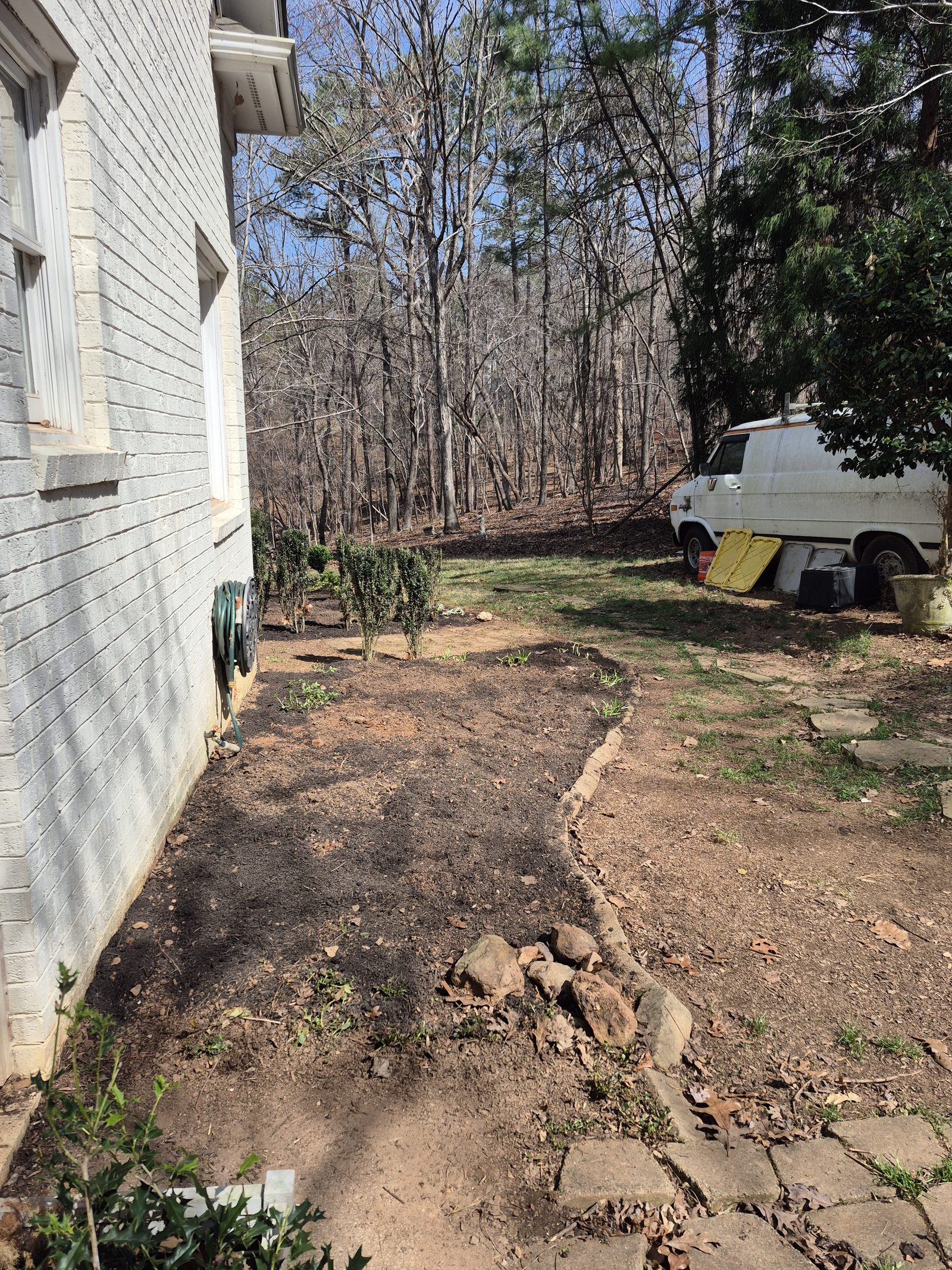 Cleared soil bed prepared alongside the house foundation